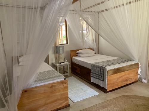 two beds in a room with white drapes at Sandy Feet Retreat in Malindi