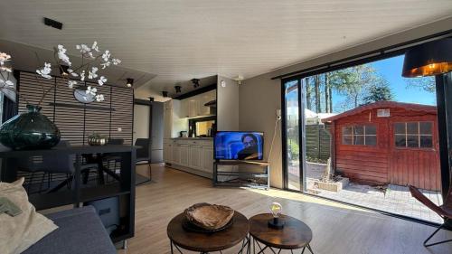 a living room with a tv and a large window at Luxe Chalet Veluwe - Perfect Getaway in Voorthuizen