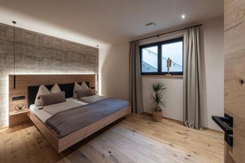 a bedroom with a large bed and a large window at Niederhof - Urlaub auf dem Bauernhof in Brixen