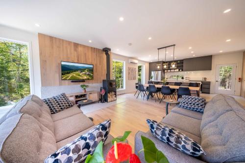 een woonkamer met twee banken en een keuken bij Sauna & Pool Table - Nordik Attitude in Saint-Philémon