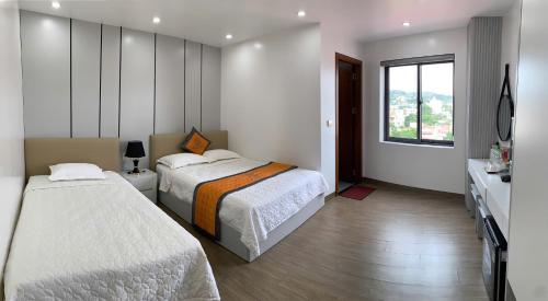 a hotel room with two beds and a window at Nhật Minh Hotel - Lạng Sơn in Lạng Sơn