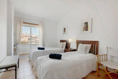 Dos camas en una habitación blanca con ventana. en Clos des Lyces, en Santa Luzia