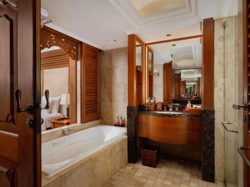 a bathroom with a bath tub and a bedroom at Nusa Dua Beach Hotel and Spa - Handwritten Collection in Nusa Dua