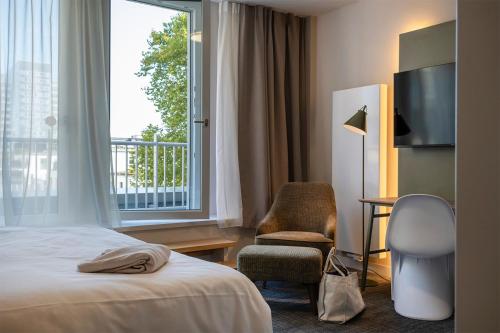 a hotel room with a bed and a chair and a window at HUB Apartments St Georg in Hamburg