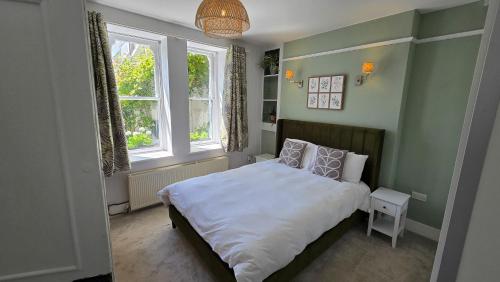 a small bedroom with a bed and two windows at Headmasters House in Port Isaac