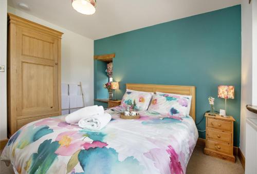 a bedroom with a large bed with a colorful bedspread at Great Ash Barn in Copplestone