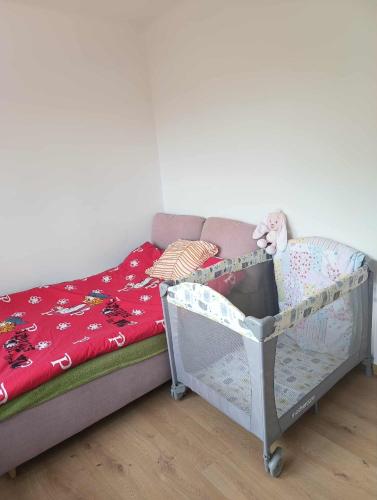 a small bed with a crib with a red blanket at Noclegi Jak u Babci in Nowe Miasto