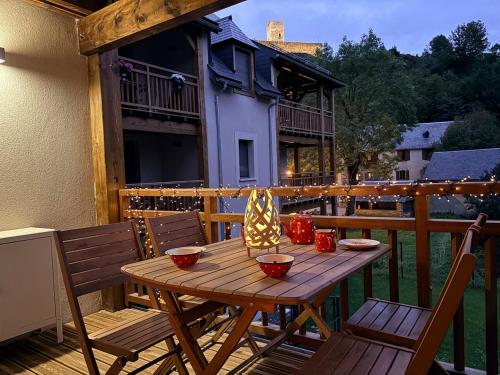 a wooden table on a deck with two chairs at Appartement cosy au bords du lac de Loudenvielle in Génos