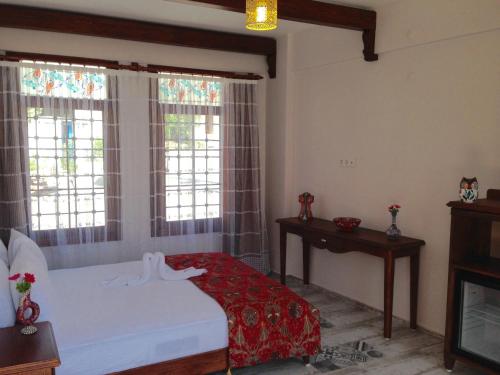 a bedroom with a bed and two windows at Hotel Mary's House in Selcuk