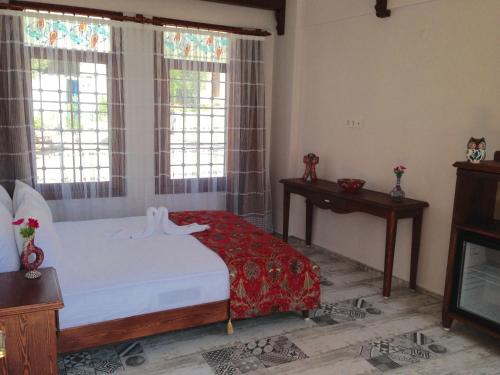 a bedroom with a bed and a table and windows at Hotel Mary's House in Selcuk