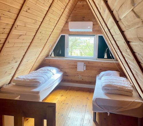 two beds in a wooden room with a window at Storkesøen Ribe Holiday Cottages and Apartments in Ribe
