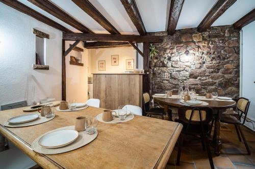comedor con mesas y sillas y pared de piedra en Chai d'oeuvre, en Dambach-la-Ville