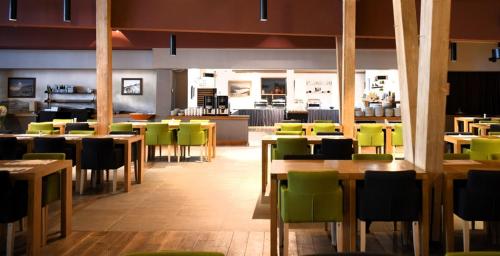 Un restaurante con mesas de madera y sillas verdes. en Jahorina Apartmani Vučko F&F, en Jahorina