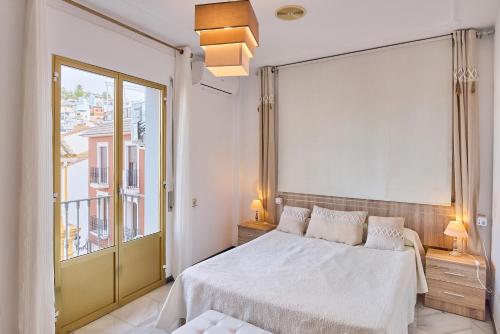 a bedroom with a white bed and a large window at Casa Filo Vistas Montaña in Rute