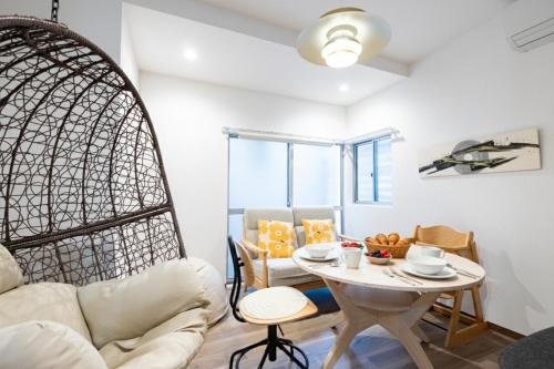 a living room with a table and a chair at K's Casa西新井 駅徒歩4分 ディズニー車26分 56m2 ハンギングチェア 下町の快い暮らし in Tokyo