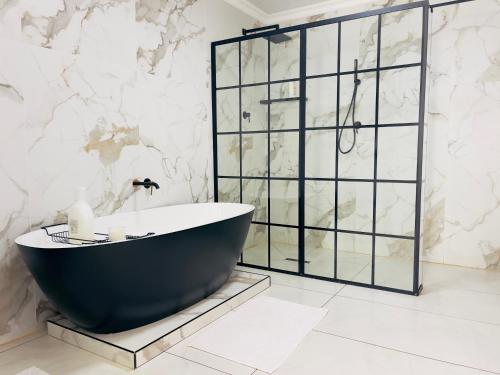 a bath tub in a bathroom with a marble wall at ANG COMSAT Guesthouse in Northam