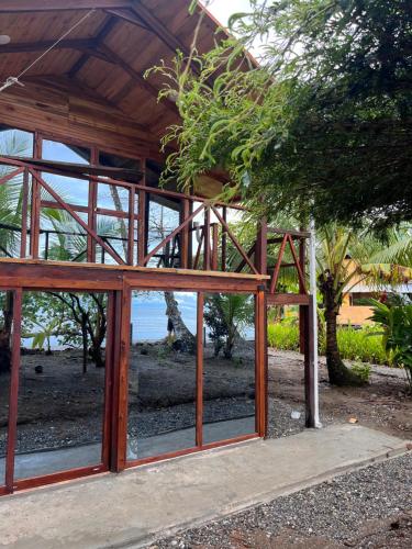 ein Holzgebäude mit Glasfenstern vor einem Strand in der Unterkunft Popochos Beach Eco Lodge in Nuquí