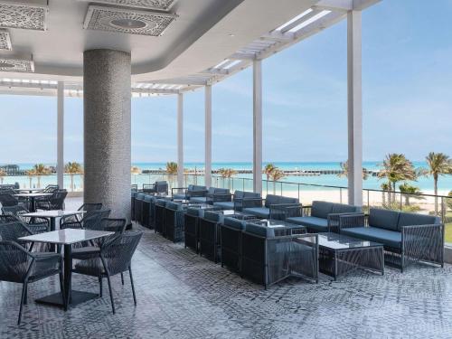 ein Restaurant mit Tischen und Stühlen und dem Meer in der Unterkunft Rixos Premium Alamein in El-Alamein