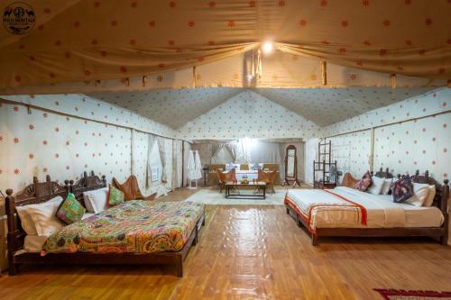 a bedroom with two beds and a table in it at Wild Heritage Desert Camp in Jaisalmer