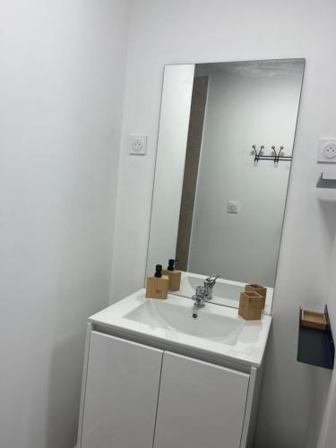 un bagno bianco con lavandino e specchio di le relais des étangs a Mareuil-Caubert
