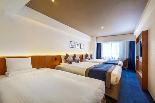 a hotel room with three beds and a window at Hotel Mystays Premier Hamamatsucho in Tokyo