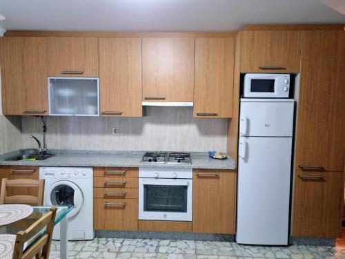Una cocina con un refrigerador blanco y un microondas. en O Curro de Arou, en Arou