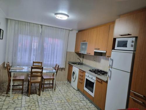 cocina con nevera blanca y mesa con sillas en O Curro de Arou, en Arou