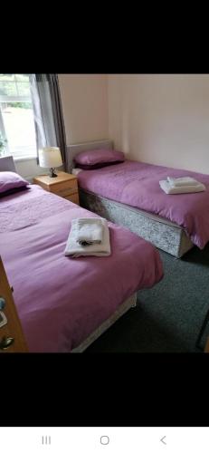 two beds in a room with purple sheets and towels at Ferns Holiday let in Glenarm