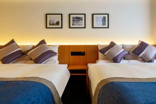 two beds sitting next to each other in a hotel room at Hotel Mystays Premier Hamamatsucho in Tokyo