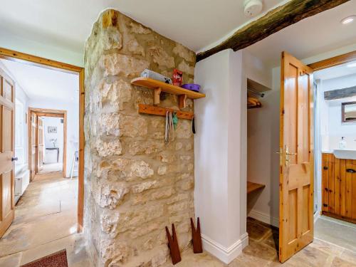 a room with a stone wall with a wooden shelf at 8 Bed in Ripon 72263 in Grantley