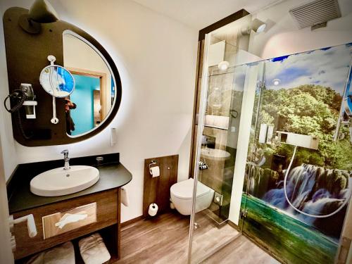 a bathroom with a sink and a shower with a mirror at Hotel Simonshof in Wolfsburg