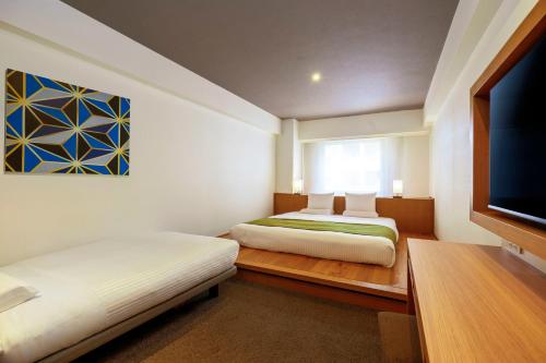 a bedroom with two beds and a flat screen tv at Hotel Mystays Premier Hamamatsucho in Tokyo