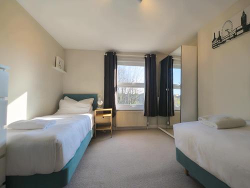 a bedroom with two beds and a window at Madison Hill - Fernlea View 4 - Two bedroom flat in London