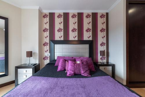 1 dormitorio con 1 cama grande de color púrpura con almohadas moradas en Apartamento Brétema, en Altamira