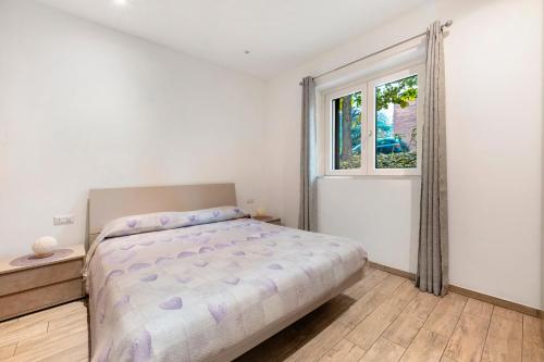 a white bedroom with a bed and a window at La Casa Di Beppe - Val d'Intelvi in Lanzo dʼIntelvi