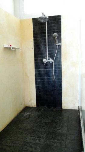 a shower in a room with a black tile wall at Nakara Samui-Superior Beach front in Ban Thong Phlu