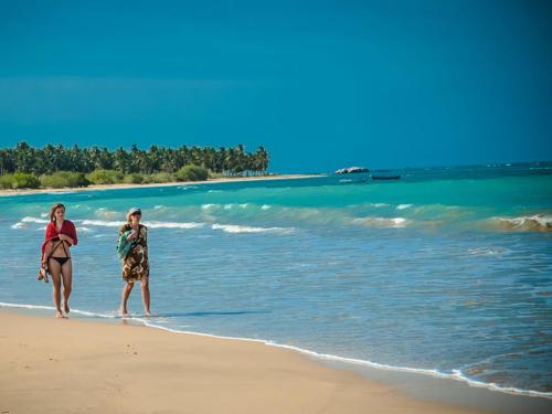 two people walking on the beach in the water at Hotel UK Pasikuda in Kalkudah
