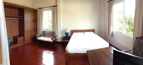 a bedroom with a bed and a chair and two windows at Nakara Samui-2 bedrooms Ocean View in Ban Thong Phlu
