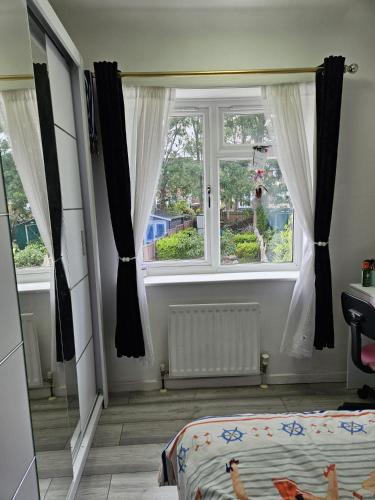 a bedroom with a bed and a window with curtains at Family Home 1 in Carshalton