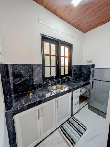 cocina con encimeras de mármol negro y nevera en Greenlight Stay, en Ambalangoda