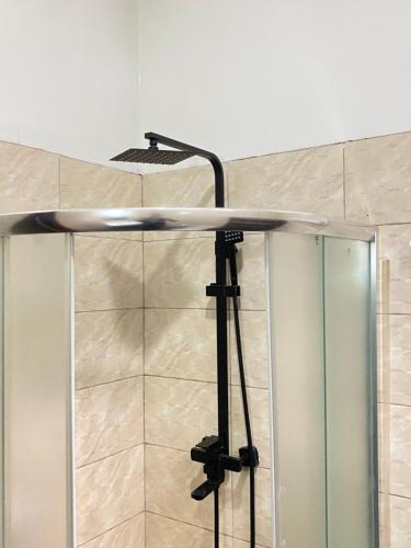 une douche avec une porte vitrée dans une salle de bain dans l'établissement Secret Stay inn and hotel, à Kigali