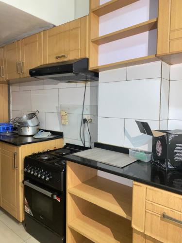 Una cocina con estufa negra y gabinetes de madera. en KIGALI SECRET STAY AND ViLLA, en Kigali