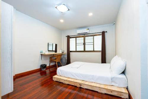 a bedroom with a bed with a window and a desk at The Hidden Sao Chingcha in Bangkok