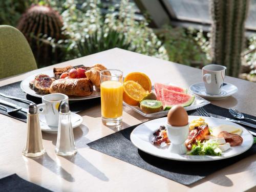 Una mesa cubierta con platos de desayuno y jugo de naranja. en Mercure Arles Centre Arenes, en Arles