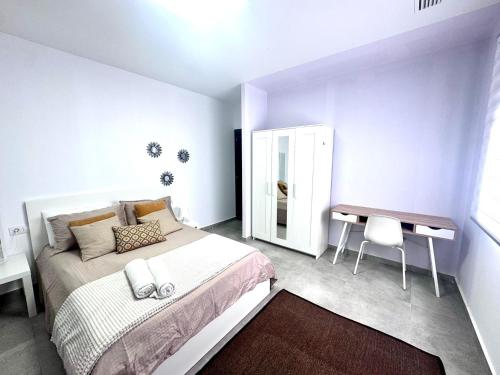 Un dormitorio blanco con una cama y un escritorio. en AZUL, en Bolnuevo
