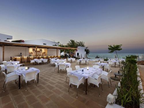 a restaurant with white tables and chairs and the ocean at Nungwi Dreams by Mantis in Nungwi