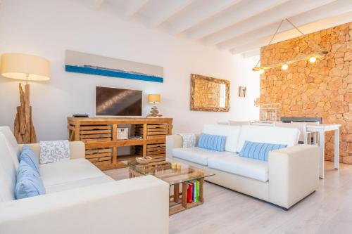a living room with white furniture and a stone wall at Can Bosquerró in Sa Ràpita