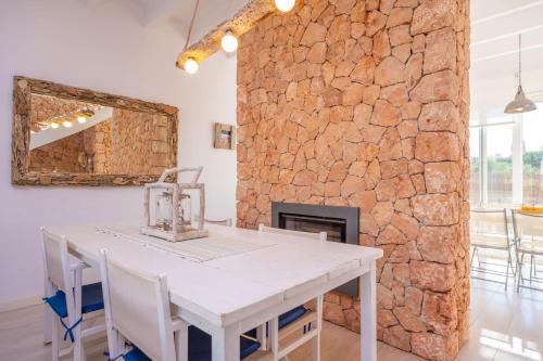 a dining room with a table and a stone wall at Can Bosquerró in Sa Ràpita