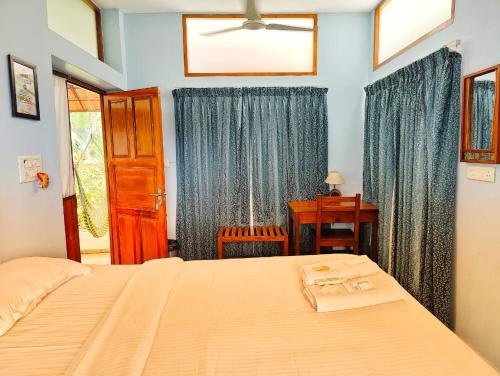 a bedroom with a bed and a desk and a window at Sun Farm Retreat in Auroville