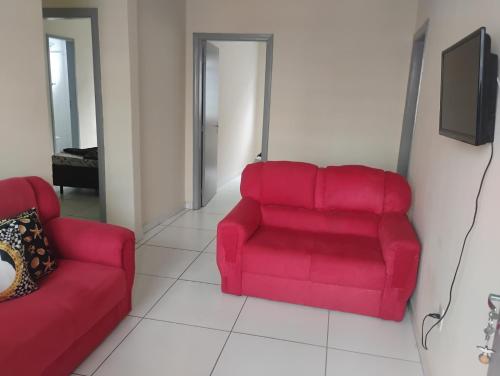 a living room with a red couch and a tv at Apartamento com 3 quartos a só 200 metros da Basílica in Aparecida